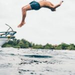 Eco-friendly Diving. - Man Wearing Blue Shorts Performing Back Flip over Body of Water