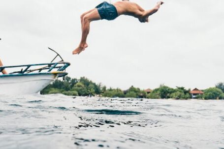 Eco-friendly Diving. - Man Wearing Blue Shorts Performing Back Flip over Body of Water
