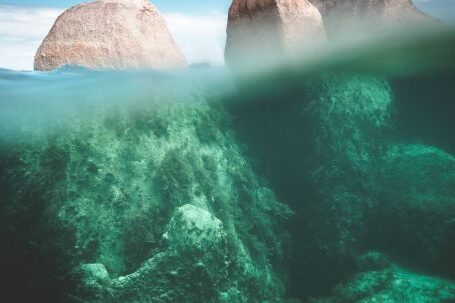 Underwater Geology. - Magnificent view of stony cliffs under transparent water of ocean in sunny summer