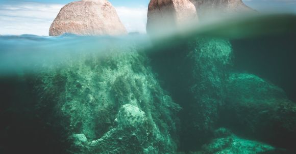 Underwater Geology. - Magnificent view of stony cliffs under transparent water of ocean in sunny summer