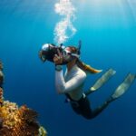 Diving Locations - a woman scubas in the ocean with a camera