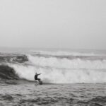 Wetsuit - Black and white side view of anonymous sportsman on surfboard practicing extreme sport on foamy ocean