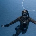 Wetsuit - Unrecognizable person diving in blue seawater