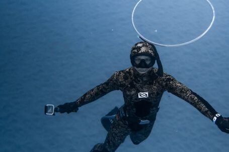 Wetsuit - Unrecognizable person diving in blue seawater