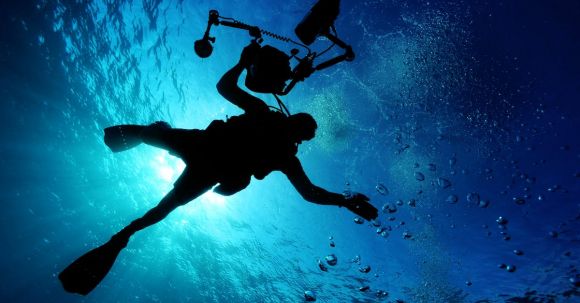 Underwater Camera - Silhouette of Person Holding Camera in Body of Water