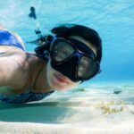 Snorkeling - woman in blue swimming goggles and swimming goggles in water