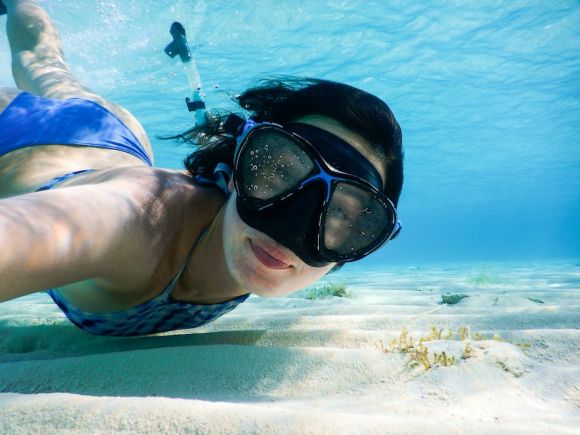 Snorkeling - woman in blue swimming goggles and swimming goggles in water