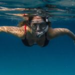 Snorkel - Unrecognizable female tourist in goggles and snorkeling mask swimming in clear blue sea during summer vacation