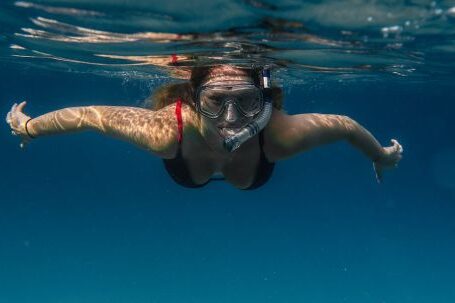 Snorkel - Unrecognizable female tourist in goggles and snorkeling mask swimming in clear blue sea during summer vacation