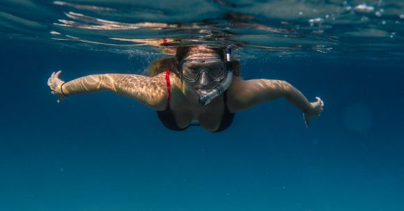 Snorkel - Unrecognizable female tourist in goggles and snorkeling mask swimming in clear blue sea during summer vacation