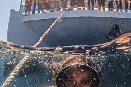 Diving Boat - Woman Underwater Taking a Picture of Herself and People on a Boat behind Her