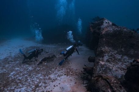 Shipwrecks For Diving - Scuba Divers with Equipment Swimming near Shipwreck Underwater