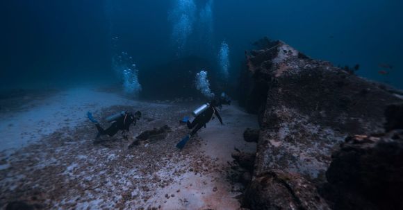 Shipwrecks For Diving - Scuba Divers with Equipment Swimming near Shipwreck Underwater