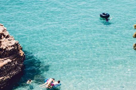 Snorkeling - Man and Woman Swimming in the Sea Near Brown Cliff