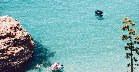 Snorkeling - Man and Woman Swimming in the Sea Near Brown Cliff