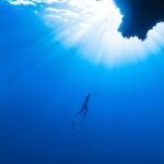 Snorkeling - a person swimming in the ocean near a cave