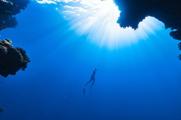 Snorkeling - a person swimming in the ocean near a cave