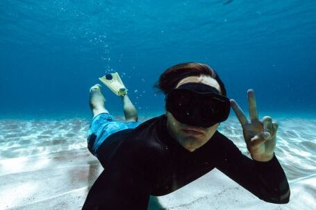 Snorkeling - Man in Clothes and Flippers Swimming Underwater