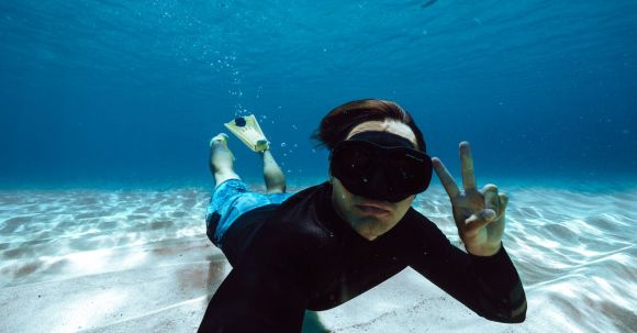 Snorkeling - Man in Clothes and Flippers Swimming Underwater