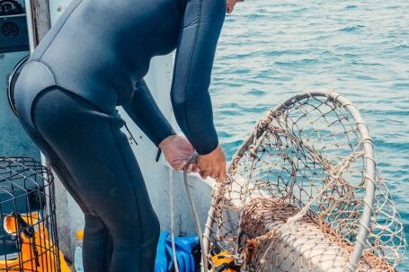 Scuba Diving - A Scuba Diver Fixing a Mesh Net Aboard a Boat