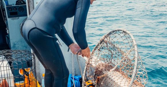 Scuba Diving - A Scuba Diver Fixing a Mesh Net Aboard a Boat