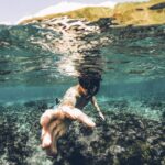 Diving - underwater photography of man wearing snorkel lending his hand