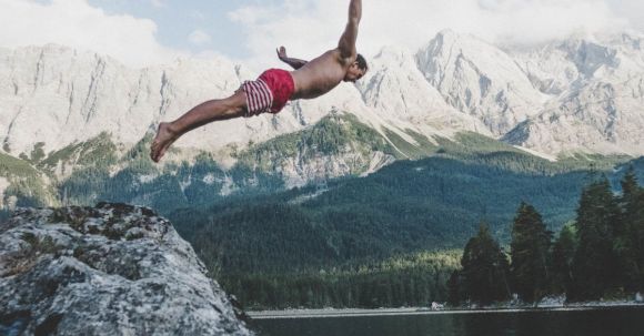 Diving - Man Wearing White and Red Board Short Diving from Rock Formation
