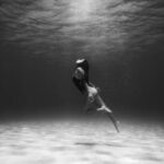 Shipwrecks For Diving - Black and White Photo of Woman Swimming Underwater 