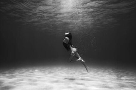 Shipwrecks For Diving - Black and White Photo of Woman Swimming Underwater 