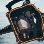 Diving - Person Grabbing Black and Orange Plastic Case Front of Calm Water