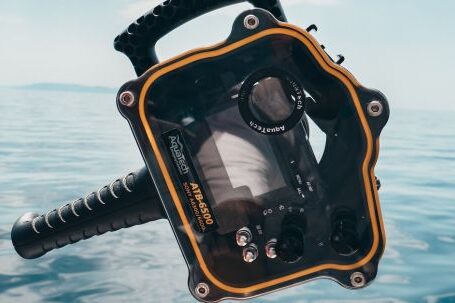 Diving - Person Grabbing Black and Orange Plastic Case Front of Calm Water