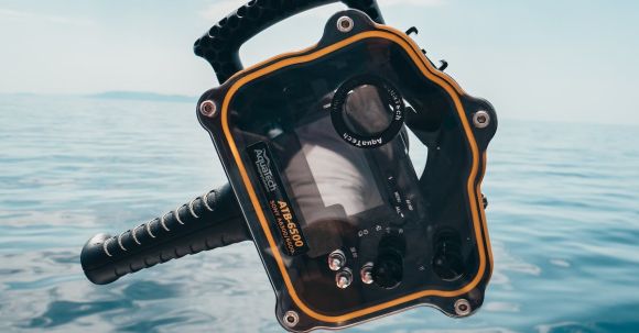 Diving - Person Grabbing Black and Orange Plastic Case Front of Calm Water