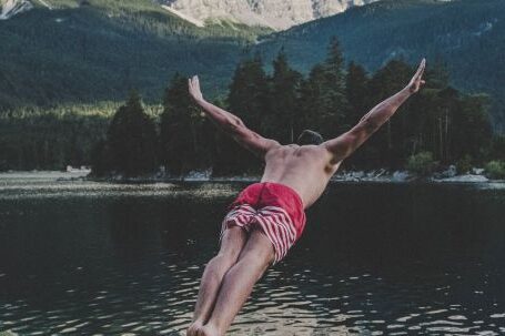 Diving - Man Wearing Red and White Striped Shorts Diving from Brown Rock