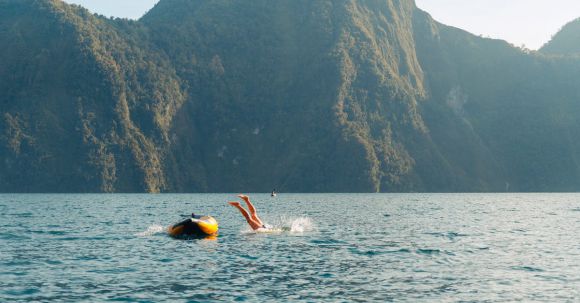 Diving Boat - A Person Diving into the Water from a Little Boat