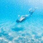 Diving Mask - Anonymous male diver swimming in bright blue water during vacation