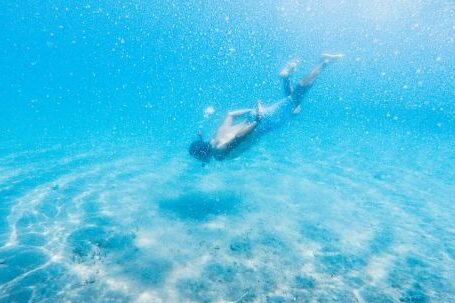 Diving Mask - Anonymous male diver swimming in bright blue water during vacation