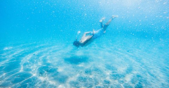 Diving Mask - Anonymous male diver swimming in bright blue water during vacation