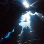 Diving - the sun shines through the water in a cave