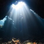 Diving - a sunbeam shines through a cave in the ocean