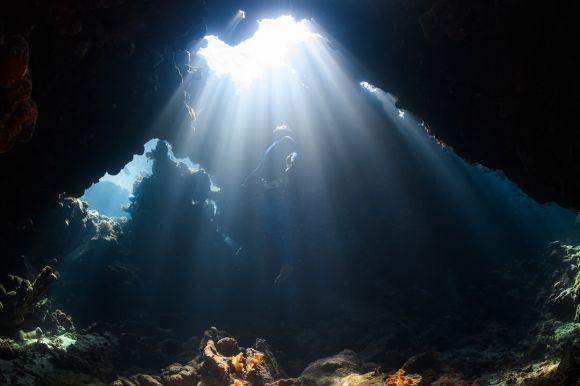 Diving - a sunbeam shines through a cave in the ocean