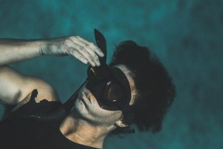 Wetsuit - From above of anonymous young male in wetsuit and snorkeling mask submerging into water while preparing for diving