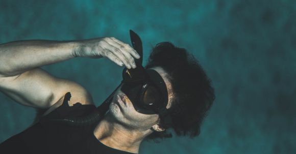 Wetsuit - From above of anonymous young male in wetsuit and snorkeling mask submerging into water while preparing for diving