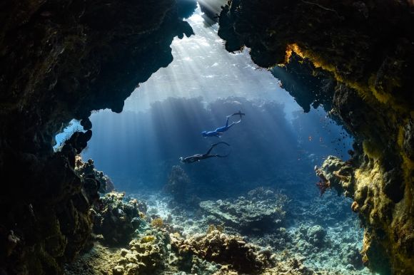 Diving Locations - a scuba diver swims through an underwater cave