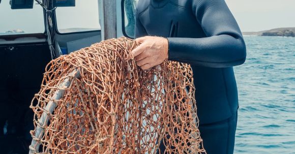 Diving Boat - Man in Black Diving Suit Holding Fishing Net on a Boat